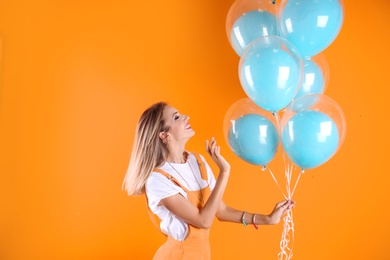 Young woman with air balloons on color background