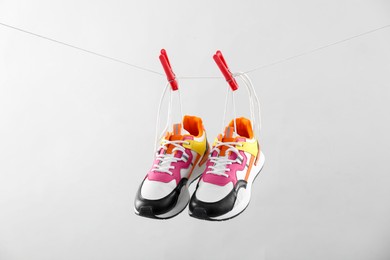 Photo of Stylish sneakers drying on washing line against light grey background