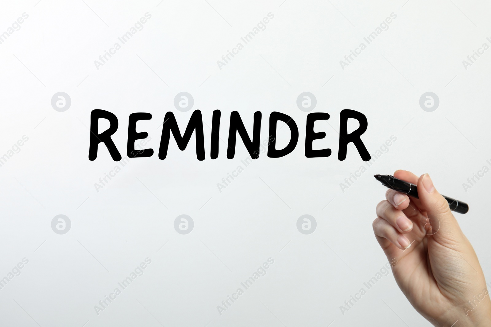 Image of Woman writing word REMINDER on glass against white background, closeup