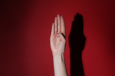 Photo of Woman showing open palm on red background, closeup