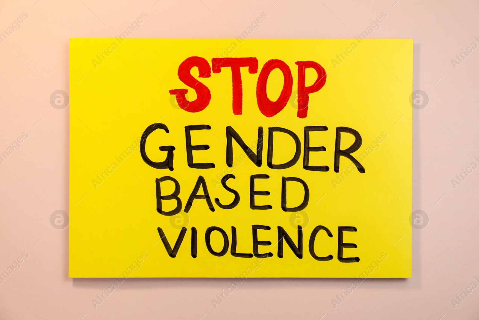 Photo of Yellow card with text Stop Gender Based Violence on pink background, top view