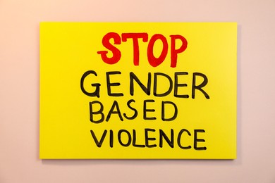 Photo of Yellow card with text Stop Gender Based Violence on pink background, top view