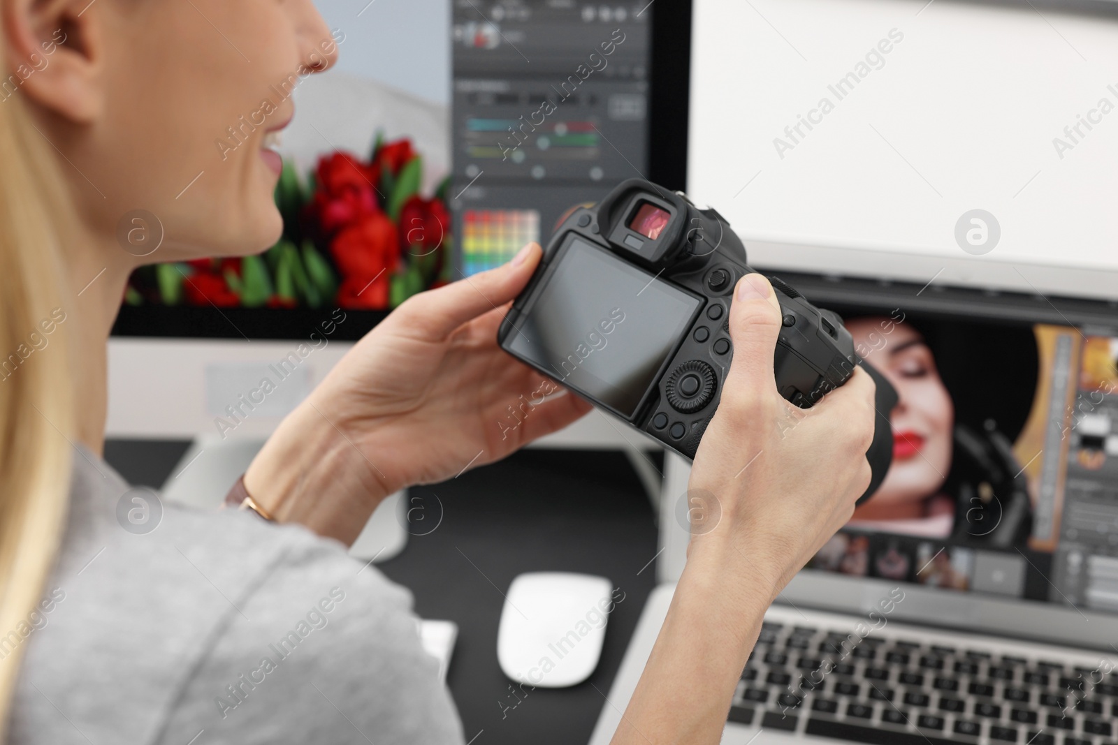 Photo of Professional photographer with digital camera at table indoors, closeup