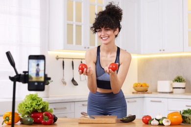 Smiling food blogger explaining something while recording video in kitchen