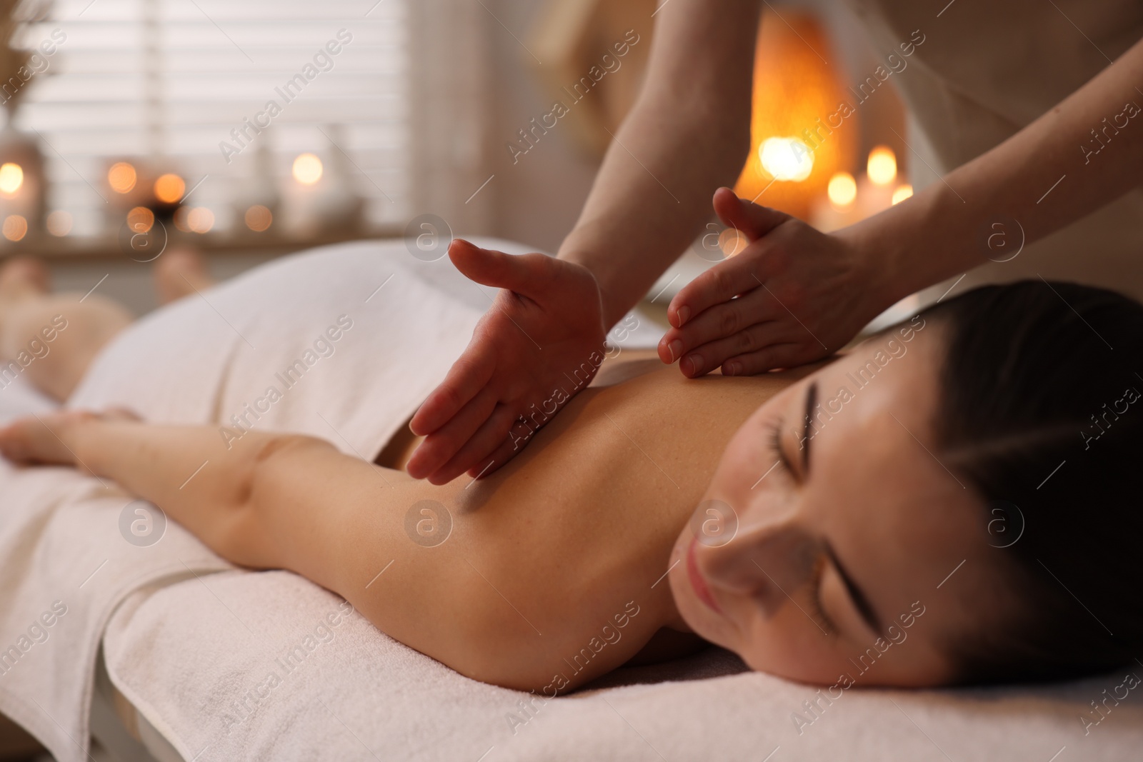 Photo of Woman receiving back massage on couch in spa salon