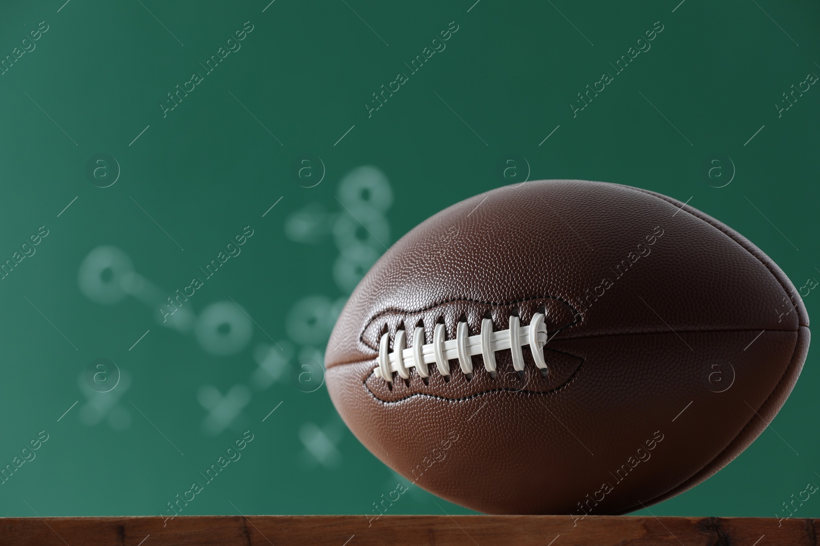 Photo of American football ball against blurred game scheme. Space for text