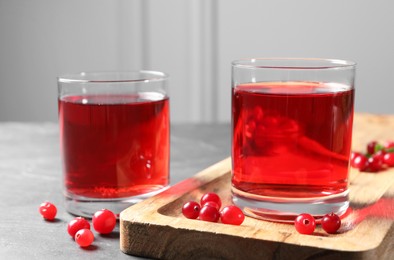 Photo of Tasty refreshing cranberry juice and fresh berries on grey table