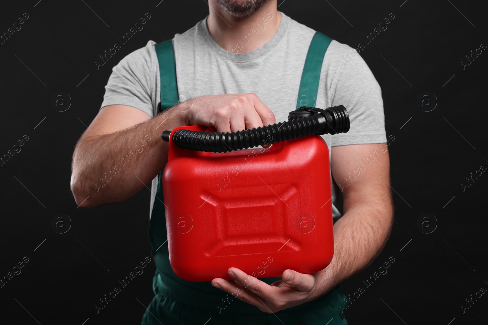 Photo of Man holding red canister on black background, closeup