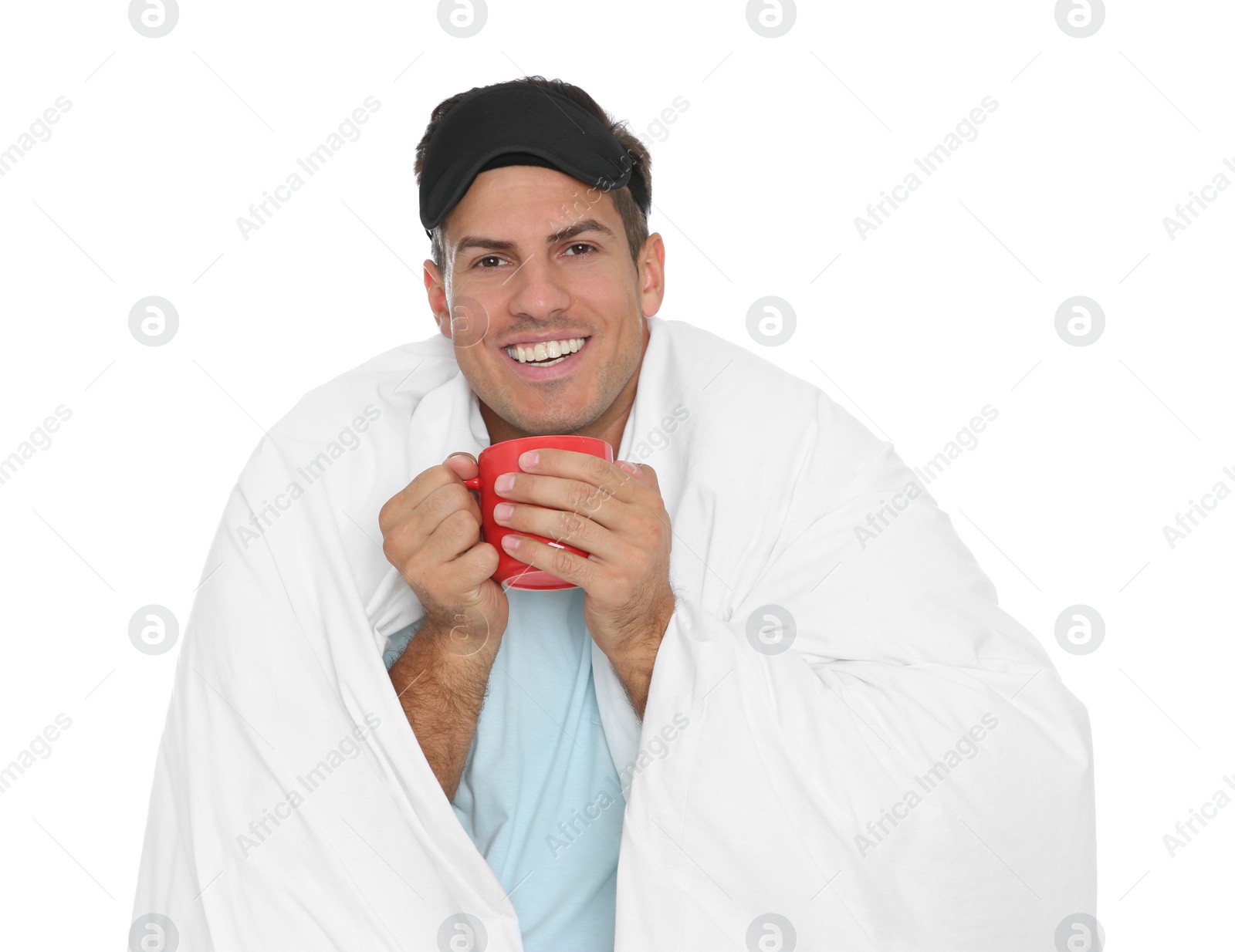 Photo of Man in sleeping mask wrapped with blanket holding cup on white background