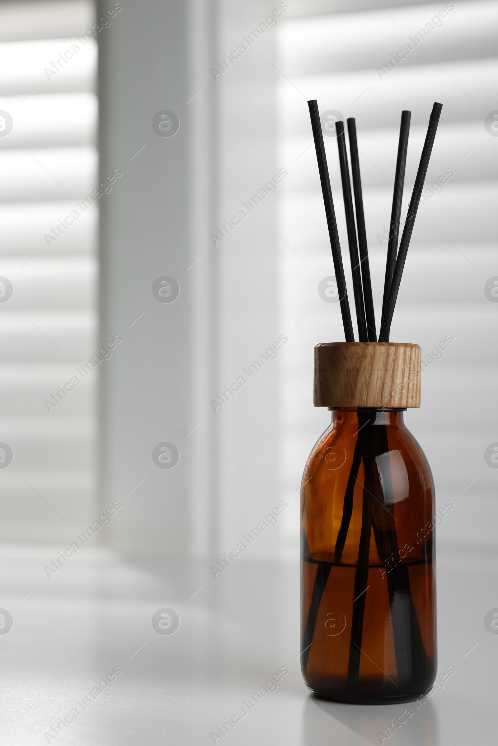 Photo of Air reed freshener on white table near window. Space for text