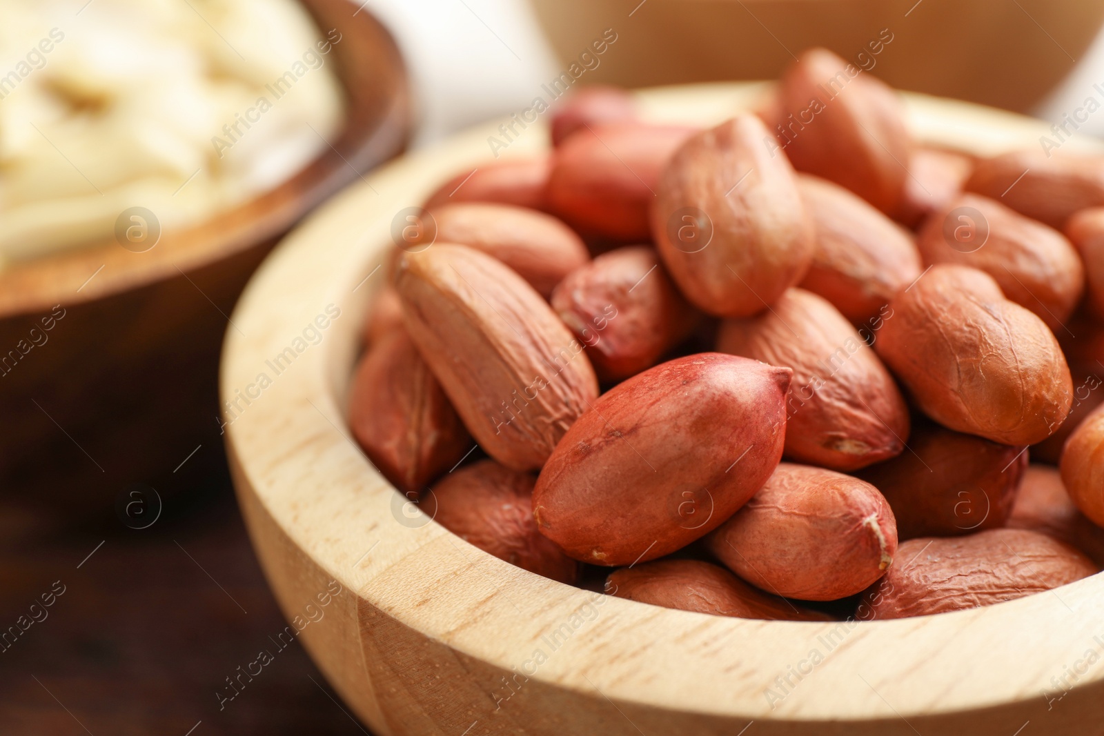 Photo of Fresh unpeeled peanuts in bowl on table, closeup