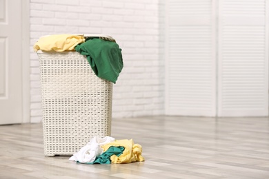 Laundry basket with dirty clothes on floor indoors. Space for text