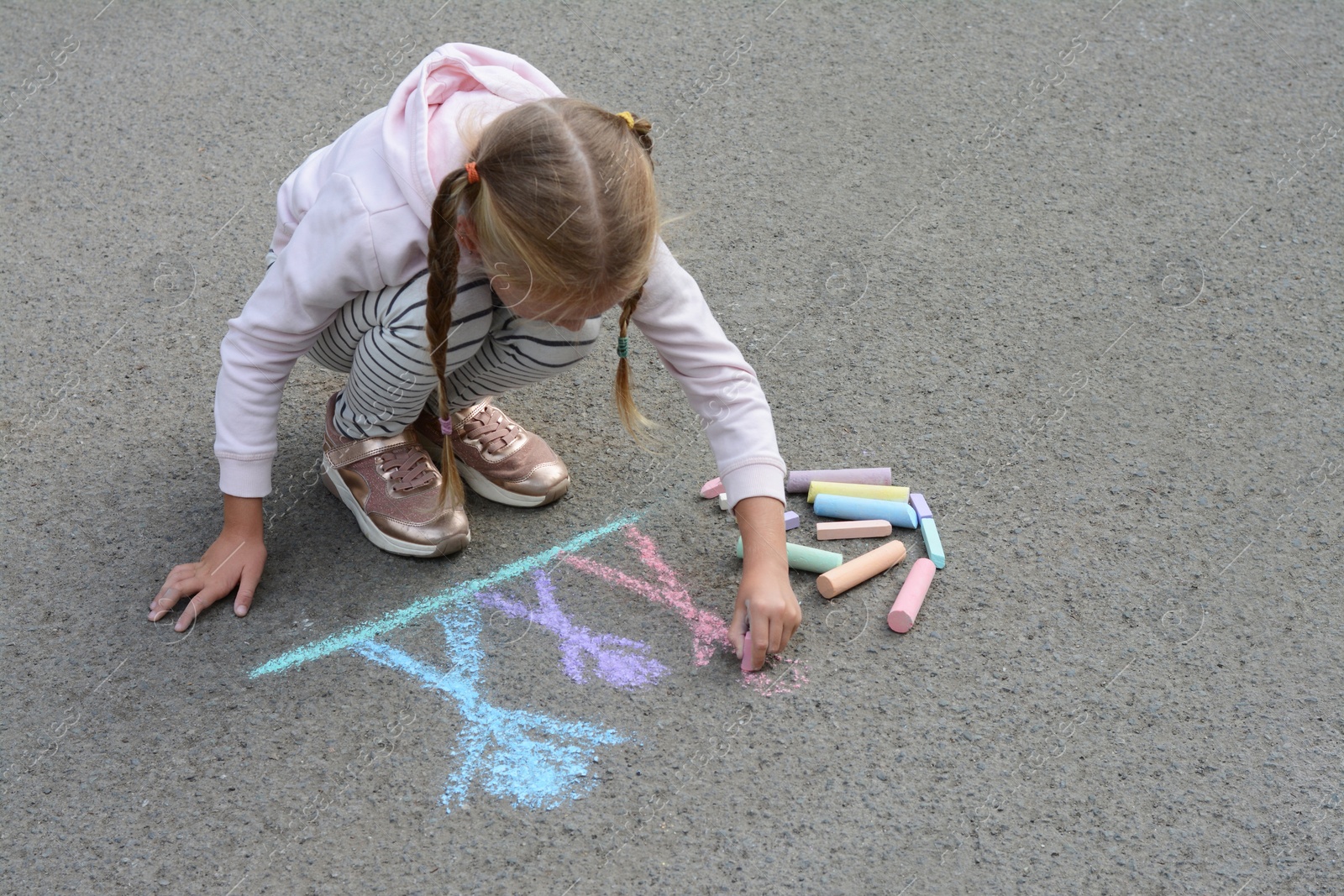 Photo of Little child drawing happy family with chalk on asphalt