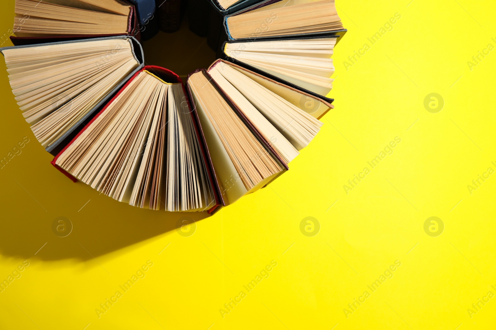 Photo of Hardcover books on yellow background, flat lay