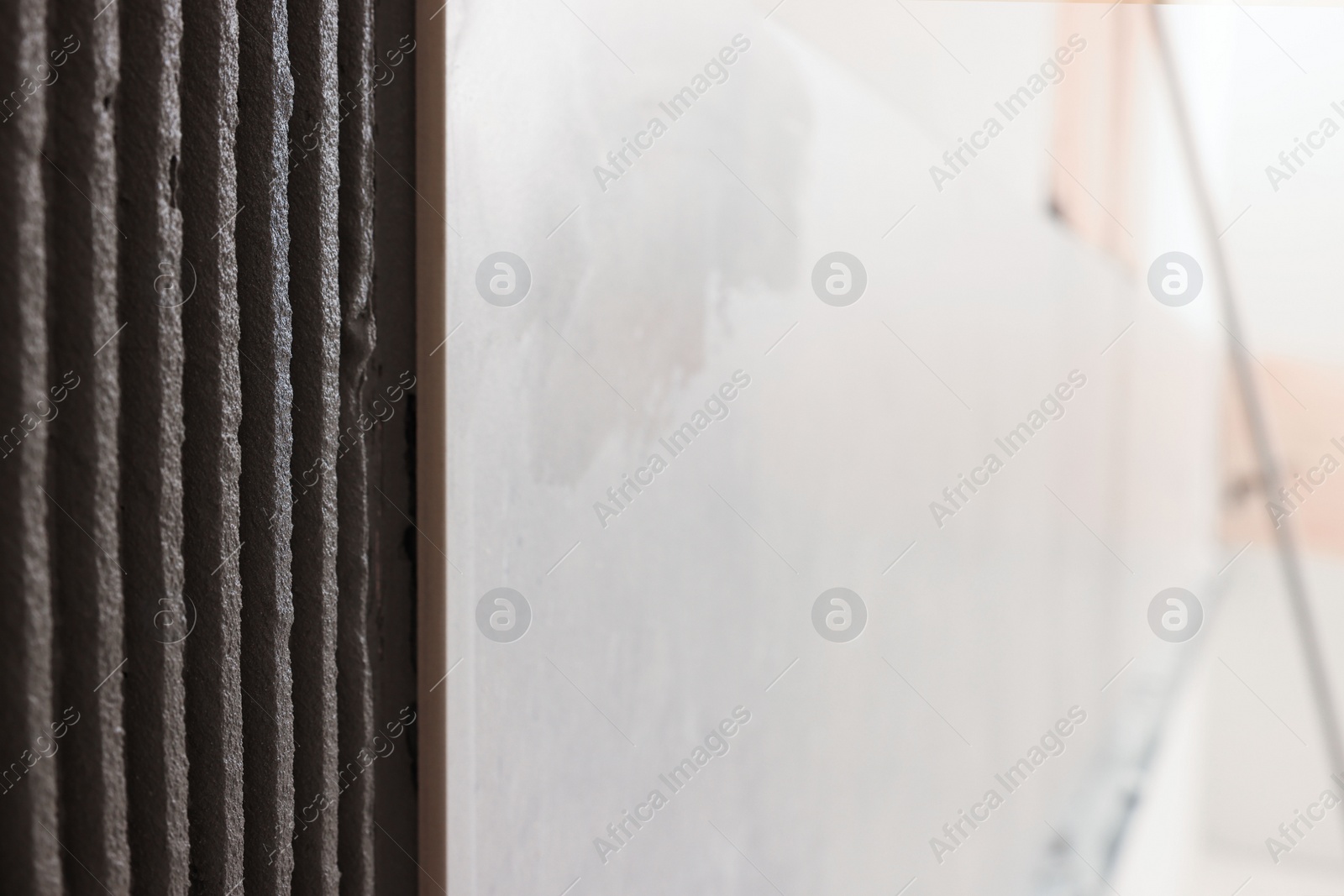 Photo of Adhesive mix and tile on wall indoors, closeup. Space for text