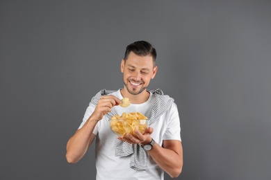 Photo of Man eating potato chips on grey background