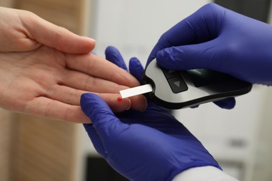 Diabetes. Doctor checking patient's blood sugar level with glucometer in clinic, closeup