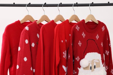 Rack with different Christmas sweaters on white background