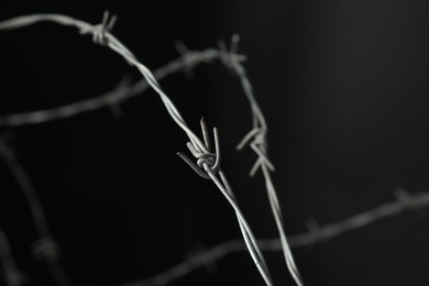 Photo of Metal barbed wire on dark grey background, closeup