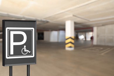 Sign with wheelchair symbol in car parking garage, space for text 