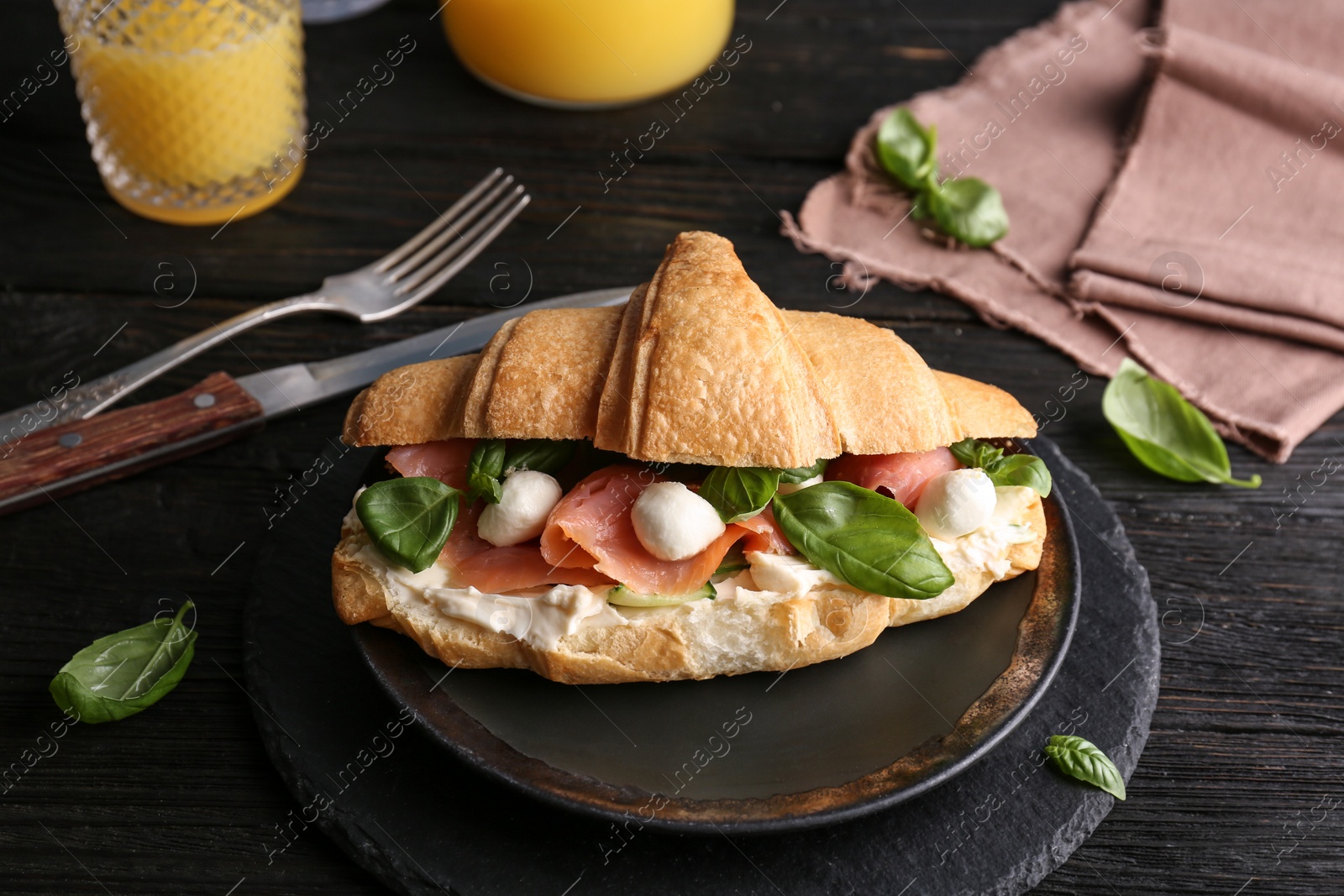 Photo of Tasty croissant sandwich with salmon on table