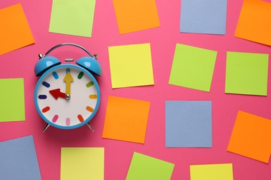 Alarm clock and blank reminder notes on pink background, flat lay