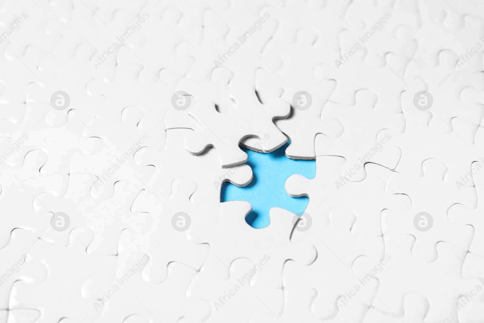 Photo of Blank white puzzle with separated piece on light blue background