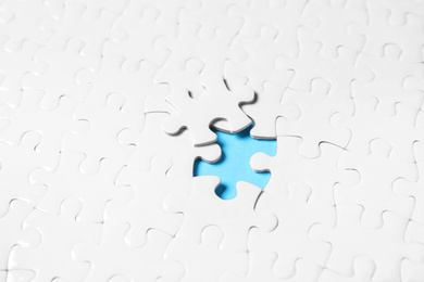 Photo of Blank white puzzle with separated piece on light blue background