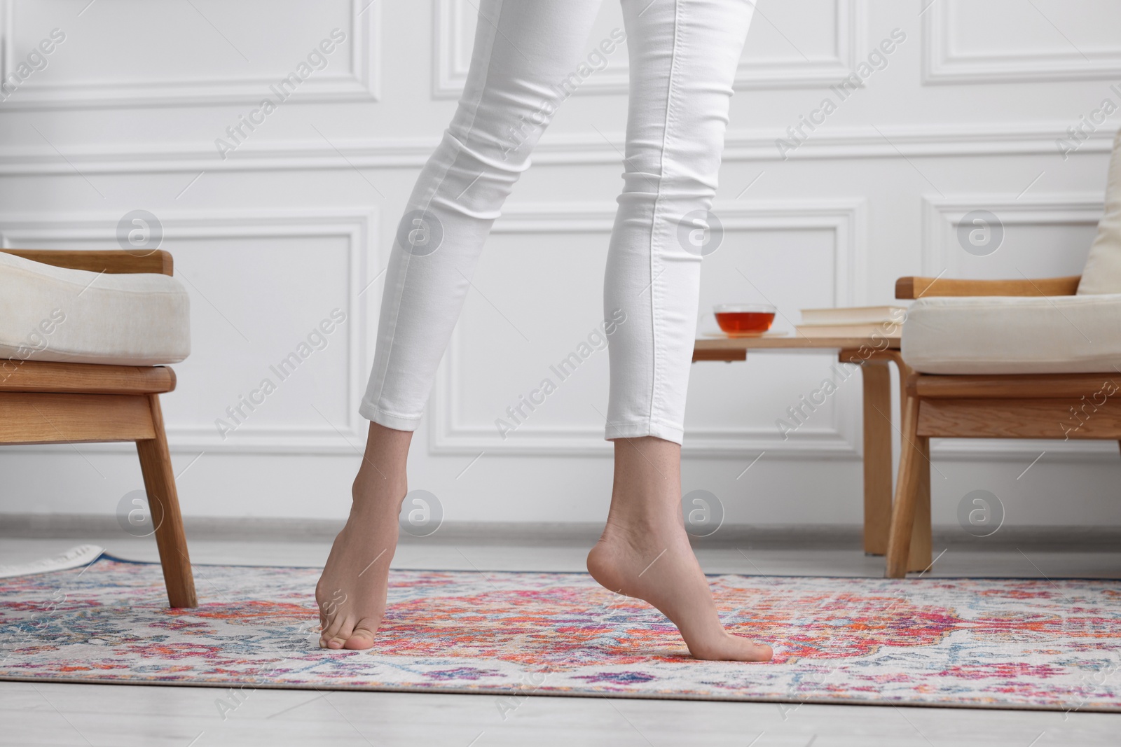 Photo of Woman standing on carpet with pattern at home, closeup