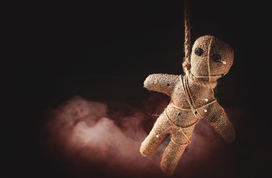 Image of Voodoo doll with pins and smoke on dark background. Space for text