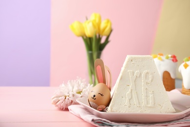 Photo of Traditional cottage cheese Easter paskha and egg with bunny ears on pink wooden table, space for text