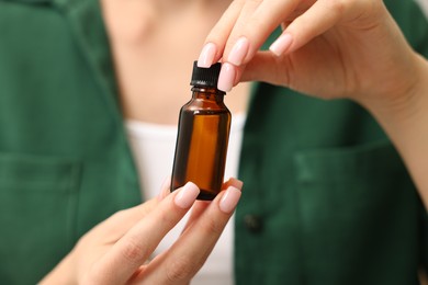 Photo of Aromatherapy. Woman with bottle of essential oil, closeup