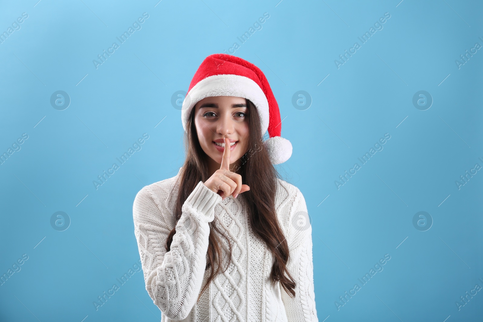 Photo of Beautiful woman wearing Santa Claus hat on light blue background