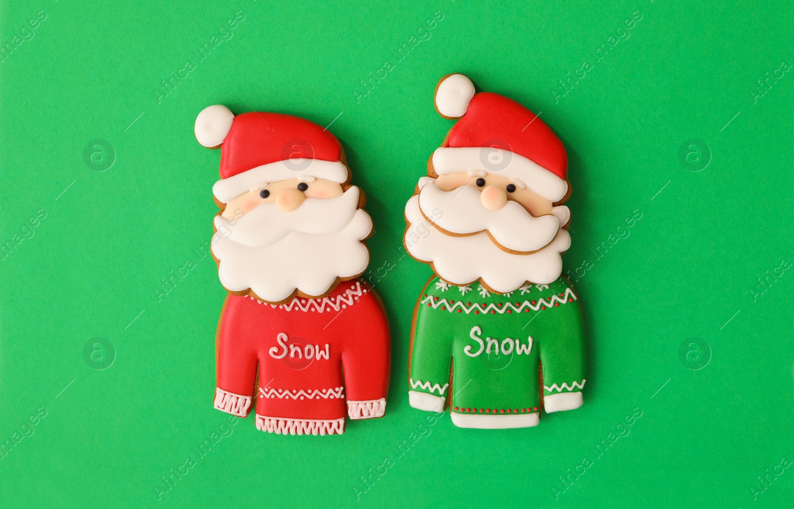 Photo of Christmas Santa Claus shaped gingerbread cookies on green background, flat lay