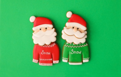 Photo of Christmas Santa Claus shaped gingerbread cookies on green background, flat lay