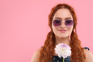 Stylish young hippie woman with dahlia flower on pink background, space for text