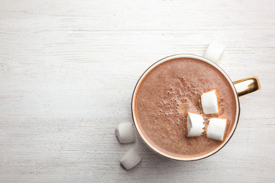 Photo of Cup of delicious hot cocoa with marshmallows on white wooden table, flat lay. Space for text