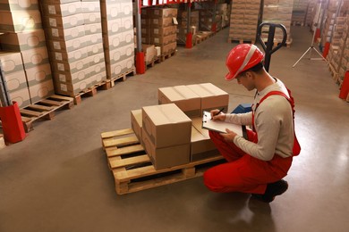 Image of Worker holding clipboard near pallet with boxes in warehouse