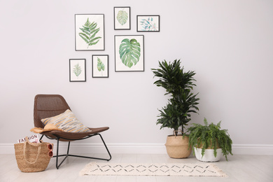 Photo of Beautiful paintings of tropical leaves on white wall in living room interior