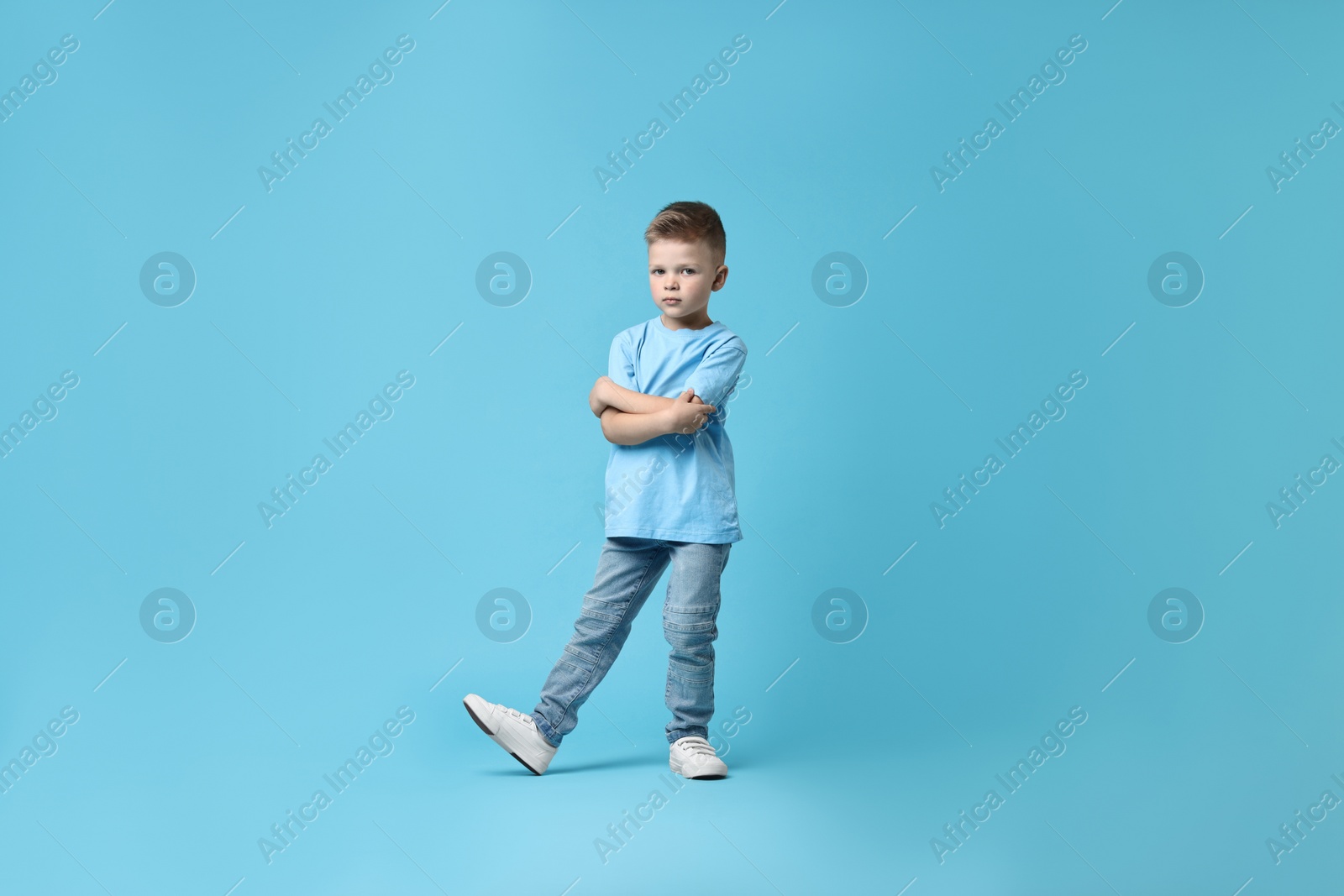 Photo of Happy little boy dancing on light blue background