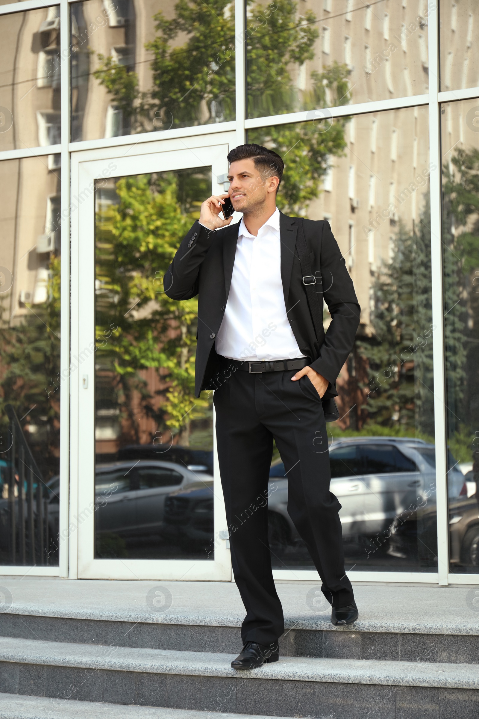 Photo of Handsome man talking on smartphone on city street