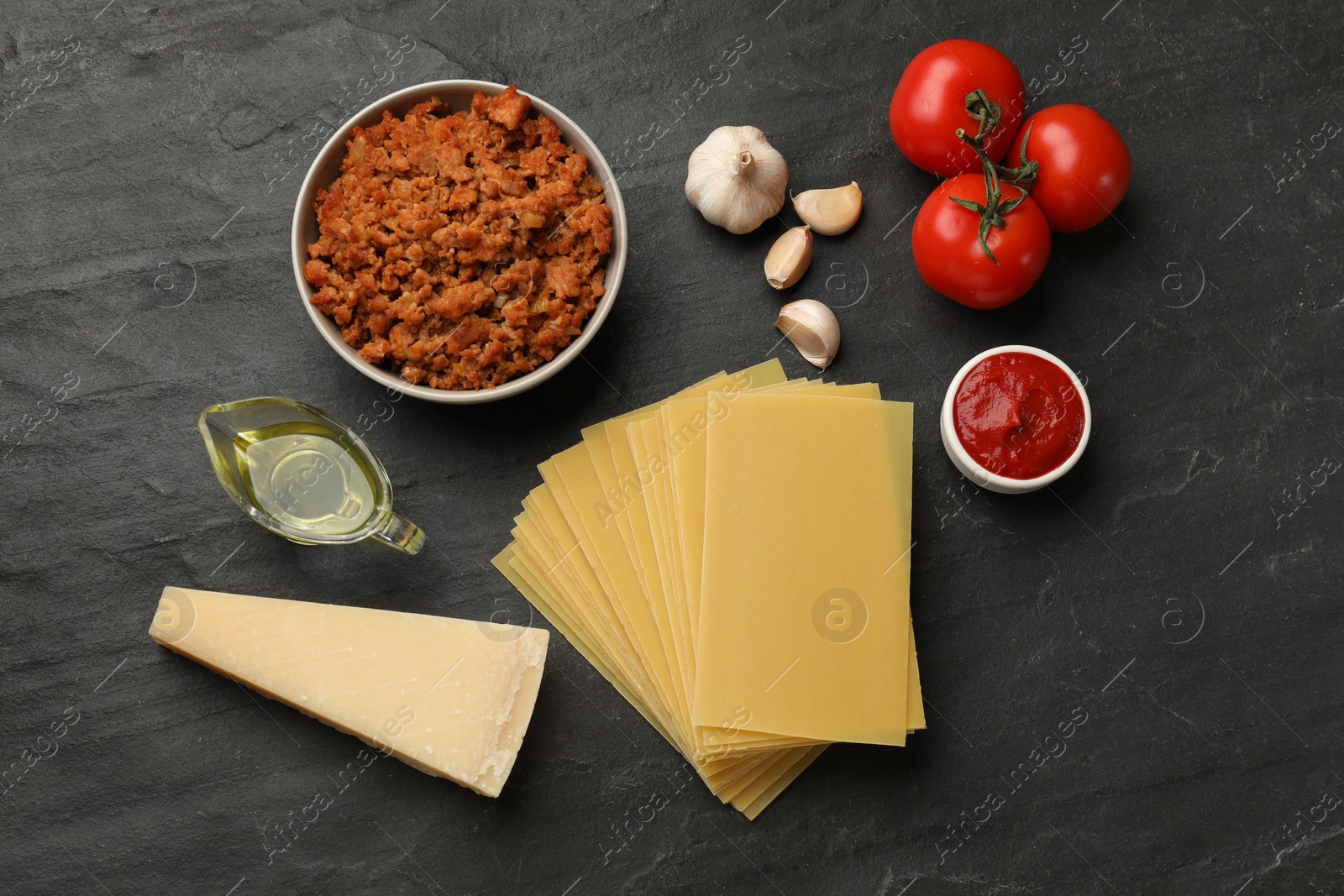 Photo of Flat lay composition with products for cooking lasagna on dark textured table