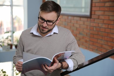 Photo of Young business man reading sports magazine at home