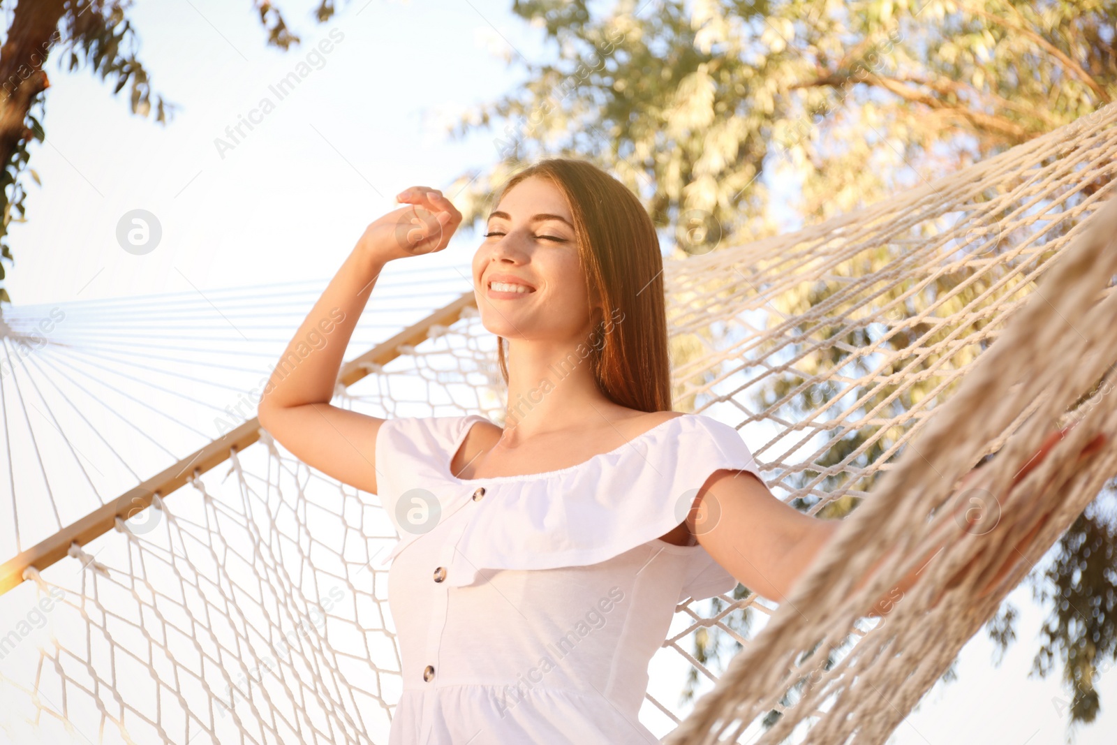 Photo of Young woman stretching in hammock on beach. Summer vacation