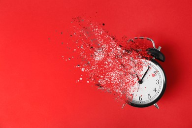 Image of Time is running out. Black alarm clock vanishing on red background, top view