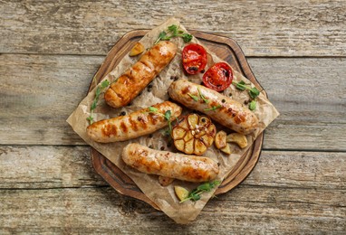 Photo of Tasty fresh grilled sausages with vegetables on wooden table, top view