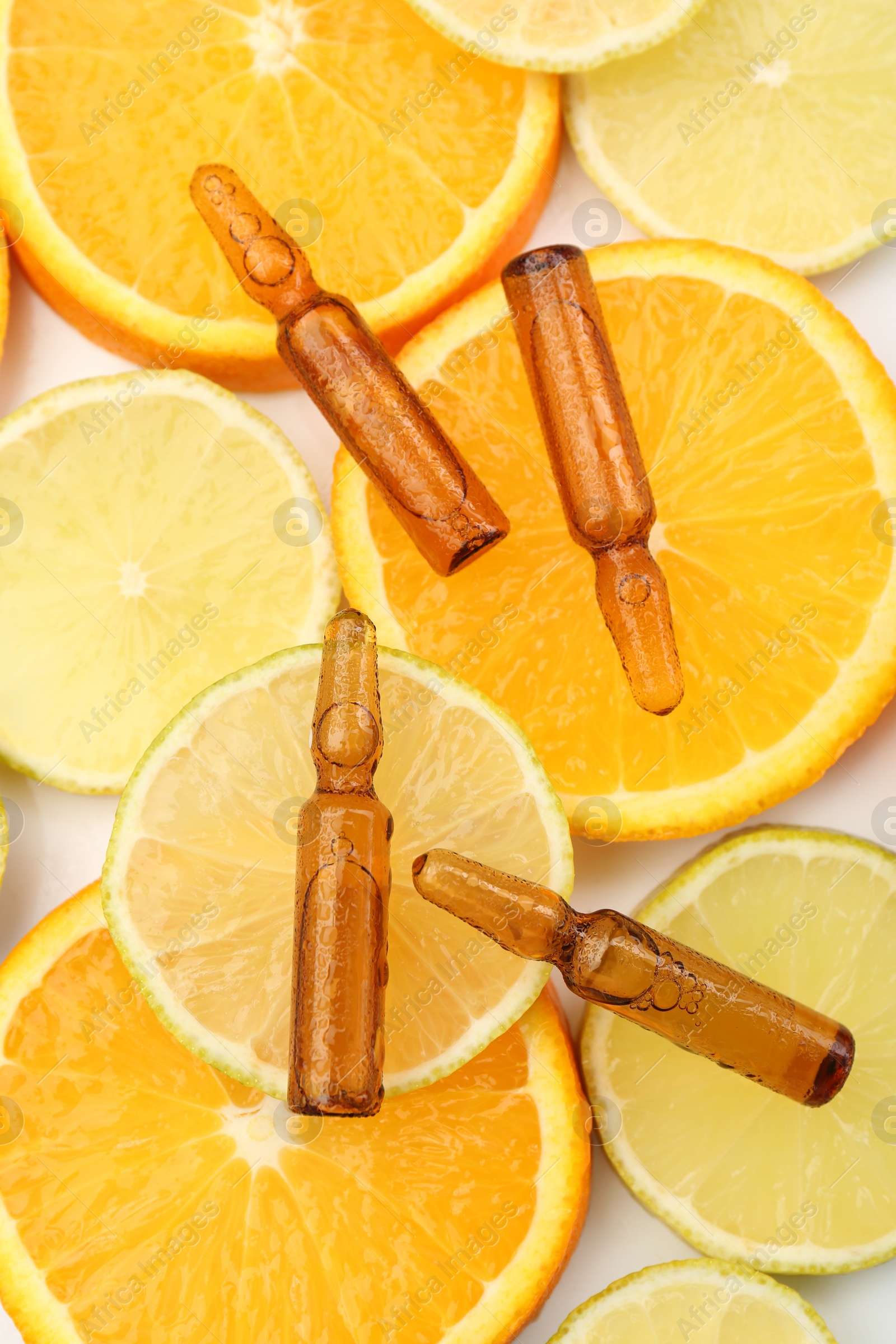 Photo of Skincare ampoules with vitamin C, lemon and orange slices on white background, flat lay