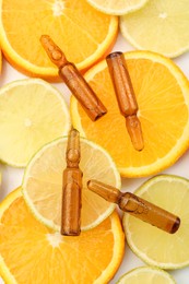 Skincare ampoules with vitamin C, lemon and orange slices on white background, flat lay