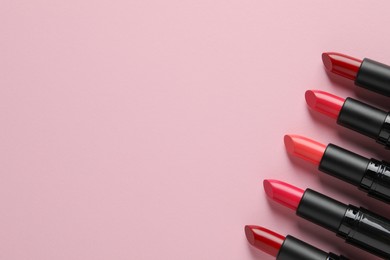 Photo of Many bright lipsticks on pink background, flat lay. Space for text