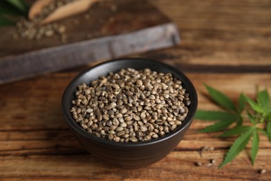 Bowl with hemp seeds on wooden table, closeup